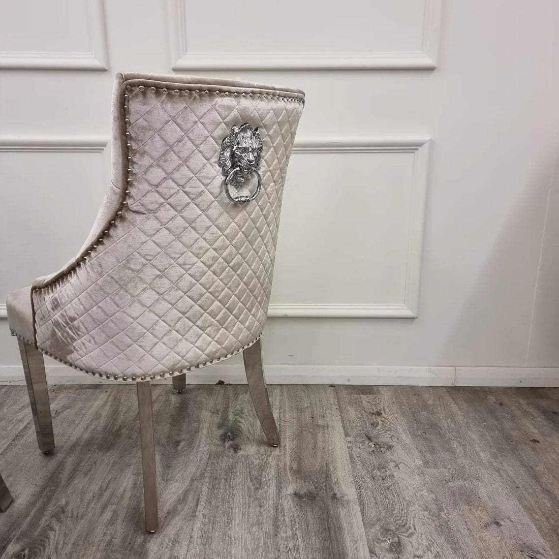 Decorative chair with quilted backrest and lion knocker on a wooden floor.