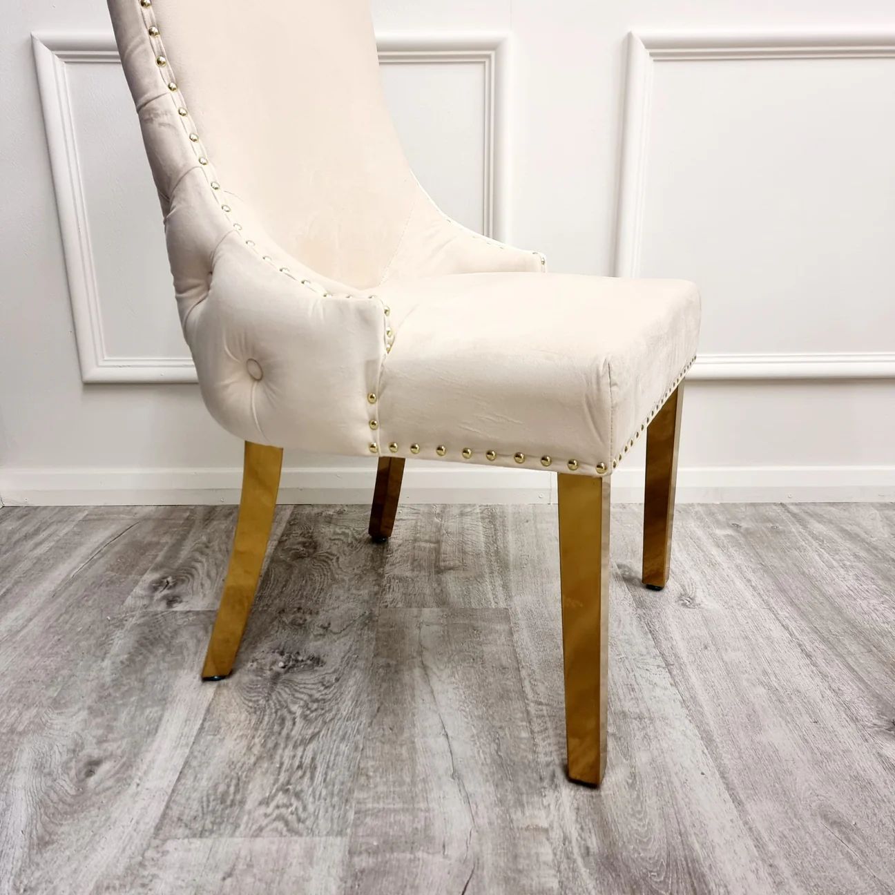Beige upholstered chair with gold legs on a wooden floor